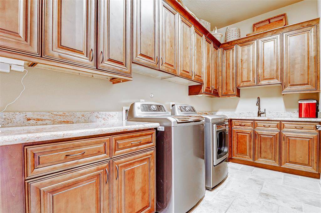 Step into the laundry room of your dreams—designed for both style and efficiency. Wall-to-wall cabinetry provides exceptional storage for all your cleaning essentials, while a convenient secondary sink adds functionality for handwashing or quick cleanups. Durable tile flooring ensures easy maintenance.