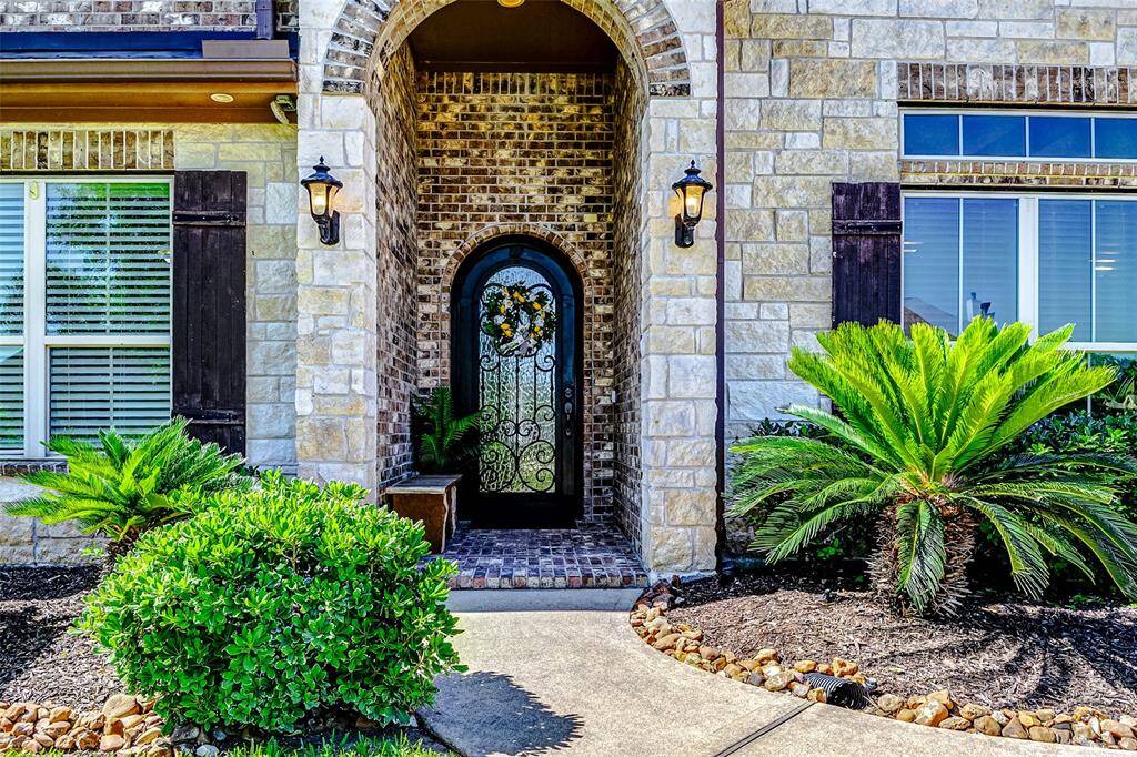 A charming paved walkway leads you to the elegant front door of this stunning residence. The striking stone and brick exterior exudes timeless elegance, beautifully complemented by rustic shutters that frame the windows with classic charm.