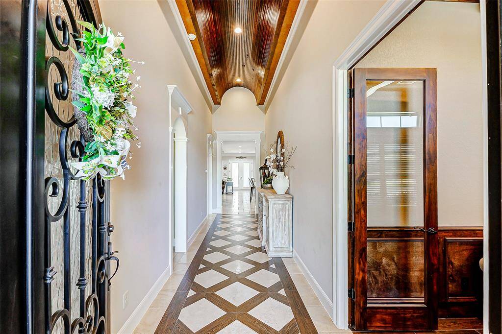 Upon entering, you're immediately embraced by a sense of elegance in the extended entryway. Soaring, barrel ceilings adorned with crown molding create a grand first impression, while sleek tile flooring—laid in an intricate diamond pattern—adds a touch of sophistication and artistry.
