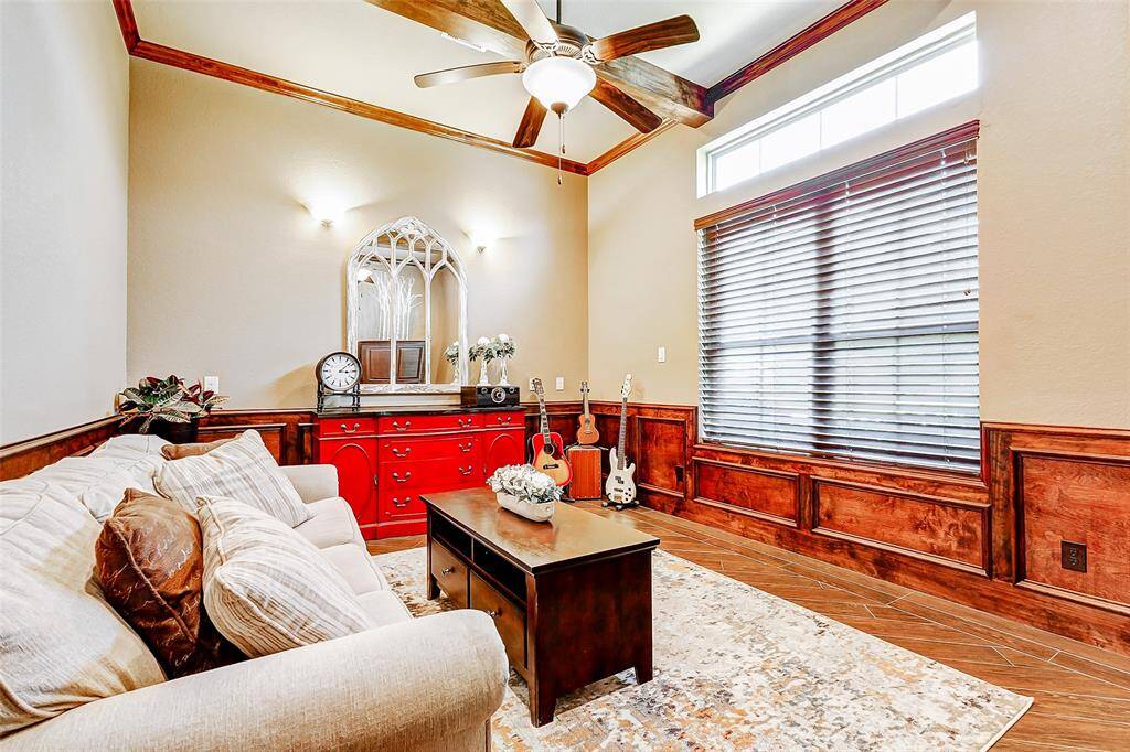 Located just off the entry for added privacy, a spacious home office awaits. Rich wood accents line the walls, while high ceilings with crown molding & a ceiling fan add both style & comfort. A large window, complemented by an elegant transom above, floods the space with natural light, creating an inspiring & serene workspace.