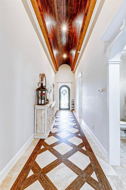 Every element of this grand entryway sets the tone for the luxury that unfolds throughout the home. High, barrel ceilings are beautifully accented with warm wood detailing, drawing the eye upward and adding architectural interest.