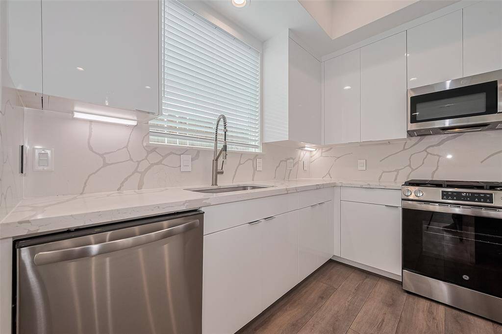 Crisp cabinetry and seamless quartz surfaces are paired with a matching backsplash, while subtle under-cabinet lighting casts a gentle glow across the counters—combining form and function beautifully.