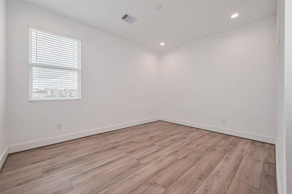 A sunlit retreat, this bedroom features wood floors, recessed lighting, and a private bath—offering both comfort and privacy.