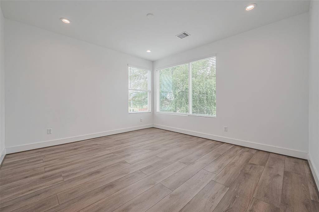 Another upstairs bedroom offers comfort and flexibility, with large windows, smooth flooring, and recessed lighting that keeps the atmosphere bright and polished.
