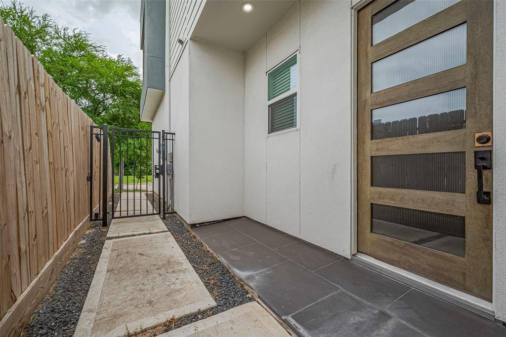 A closer look reveals the front door subtly tucked to the side, accessed through a gated walkway. The contemporary door design—featuring horizontal glass panels—hints at the thoughtful details found throughout the home.