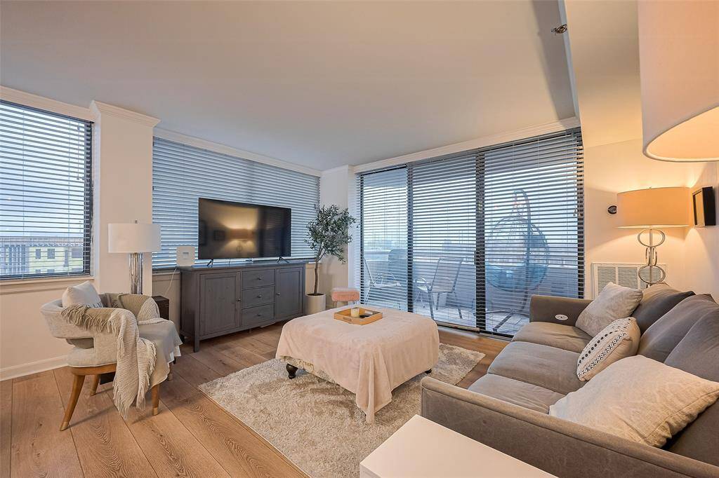 Sliding glass doors frame captivating city views and open onto the private balcony, flooding the living room with natural light and connecting indoor comfort to the outdoor skyline.