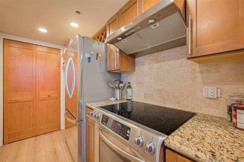 Rich wood-toned cabinetry pairs with speckled granite countertops, offering both visual warmth and lasting durability.