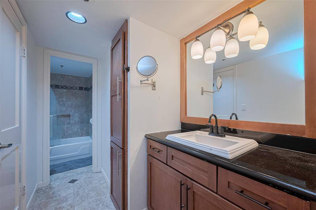 The en suite bath is appointed with a sleek vanity and generous lighting, striking the perfect balance between form and function.