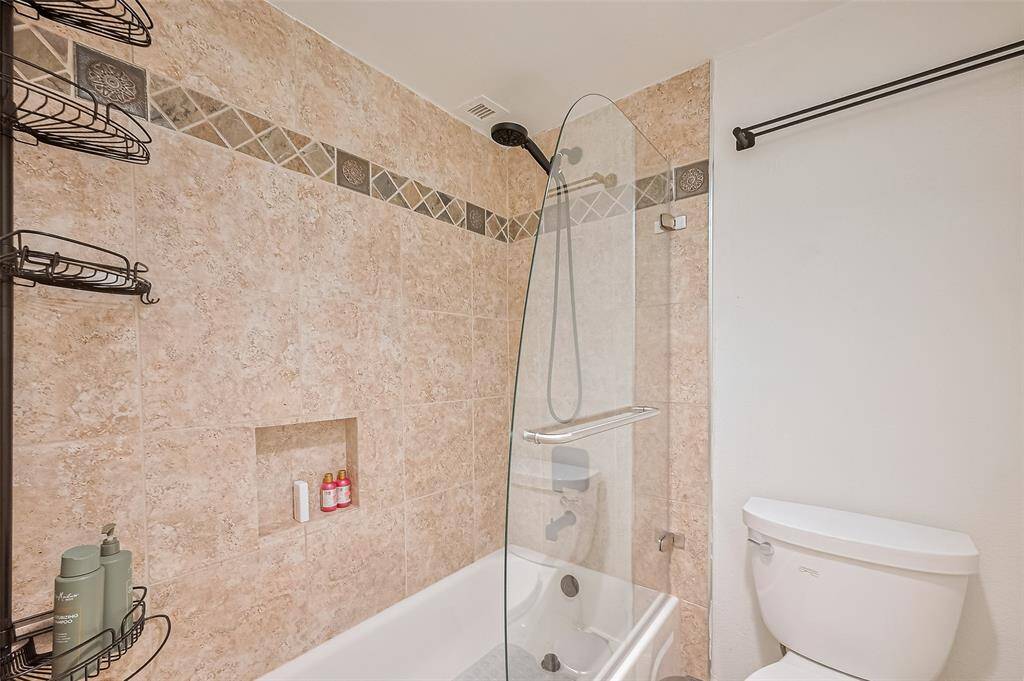 A glass divider adds a refined touch to the combined shower and tub, offering both functionality and style in the secondary bath.
