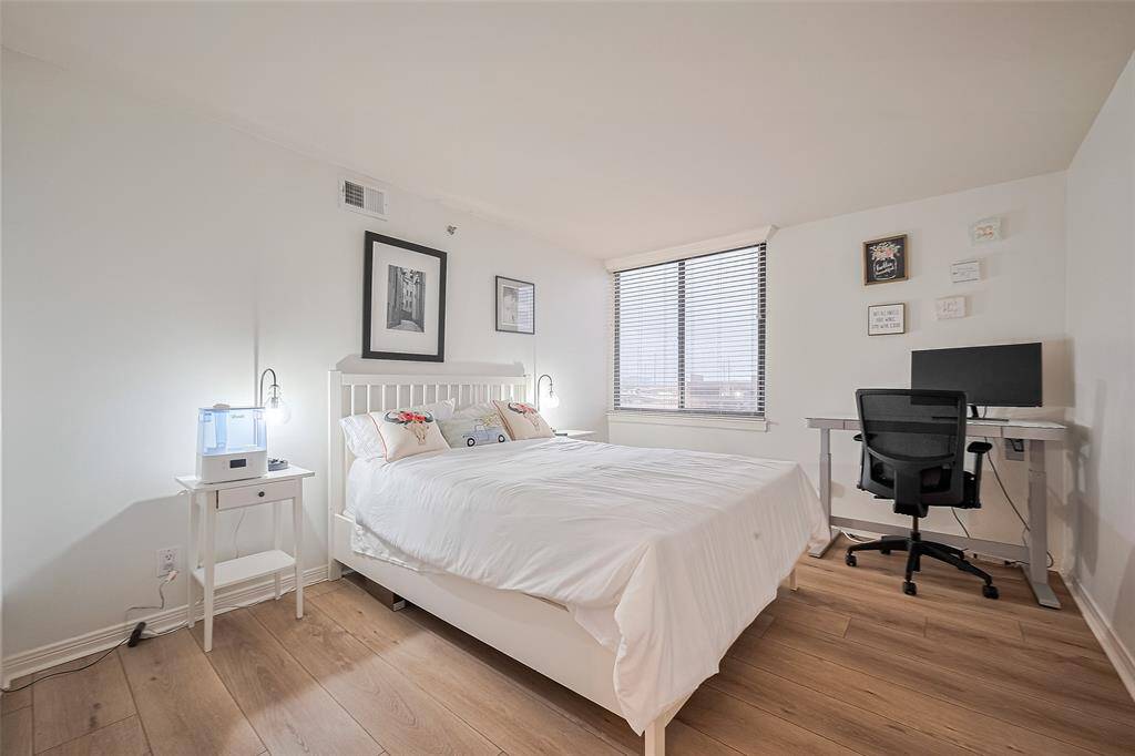 This secondary bedroom is filled with natural light from a large window and offers enough space for a bed and dedicated work area.