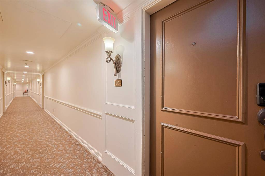 Outside the unit door, a softly lit hallway sets an elegant tone with warm sconces and a cozy design.
