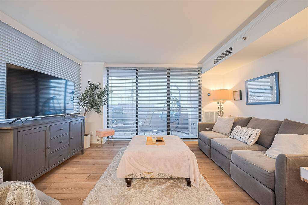 Bathed in sunlight from the windows and glass doors, this bright living area offers a warm space to unwind above the city bustle.