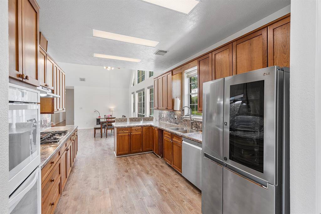 This kitchen boasts ample wooden cabinetry, sleek  countertops, and modern appliances, offering a spacious and functional cooking area ideal for any home chef.