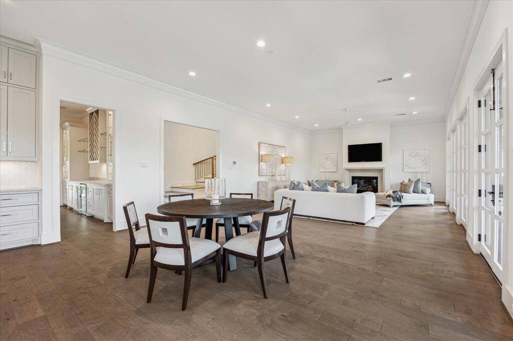 This bright breakfast area sits between the kitchen and living room, offering a casual dining space that blends seamlessly into the open-concept layout and enjoys views through walls of windows and French doors.