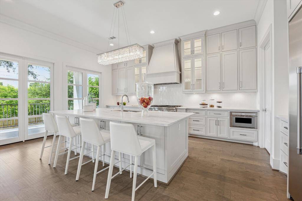This chef’s kitchen features sleek dolomite countertops, an oversized island with seating, and extensive cabinetry that combines style with ample storage, all framed by large windows bringing in natural light.