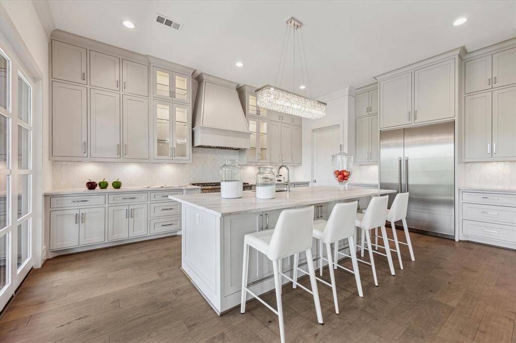 This kitchen impresses with its expansive island seating, full-height custom cabinetry, and professional-grade appliances, all designed to combine functionality with a bright, elegant atmosphere.