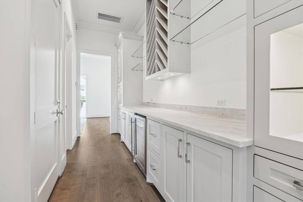 This expansive butler’s pantry offers extensive cabinetry, open shelving, a built-in wine rack, and a beverage fridge—perfect for seamless entertaining and additional prep space.