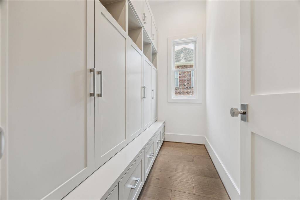 This mudroom features extensive built-in cabinetry, cubbies, and drawers for organized storage, with a bench area and a bright window that brings in natural light.