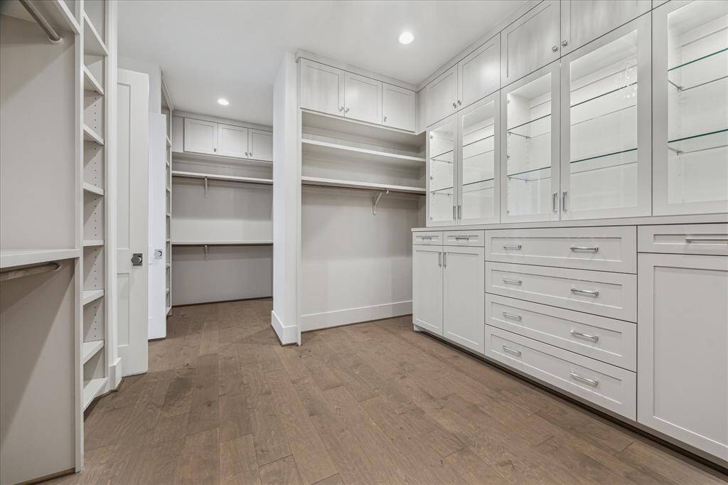 This luxurious primary closet is thoughtfully designed with custom shelving, glass display cabinets, and abundant hanging space, offering a well-organized layout that feels both spacious and refined.