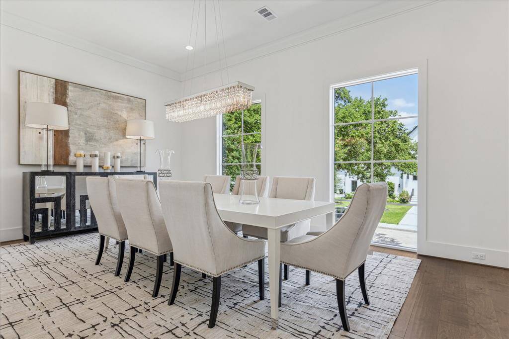 This formal dining room is filled with natural light from oversized windows and features tall ceilings and elegant crown molding, creating a bright and refined setting for gatherings.