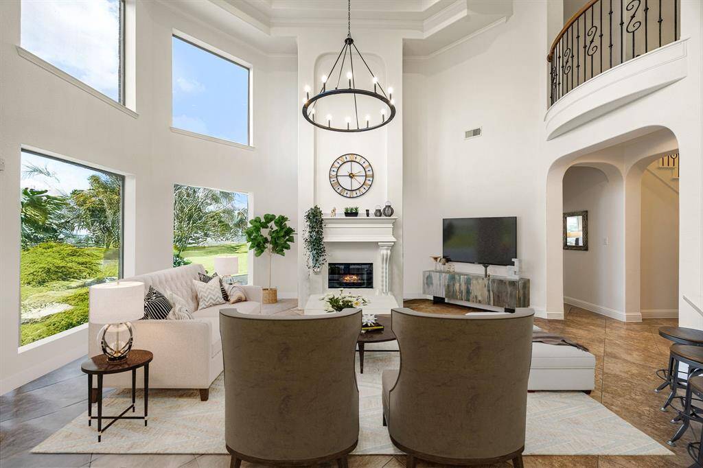This living room is more like a GREAT room featuring a stunning fireplace with mantel detailing, custom paint, soaring high ceiling, recessed lighting, dark stained ceiling fan, and an amazing wall of windows providing a lovely view of your backyard to keep an eye out on the kids or pets playing. *Virtually Staged