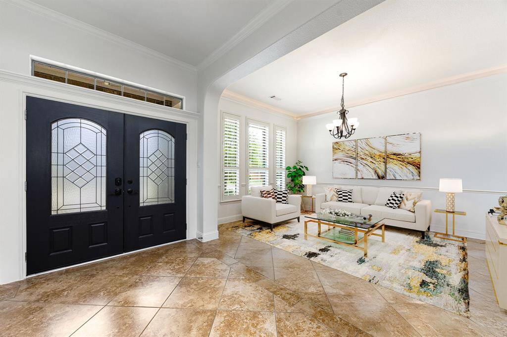Elegant formal living room with abundant natural light, plantation shutters, crown molding, and a sophisticated layout ideal for entertaining or relaxing in style. *Virtually Staged