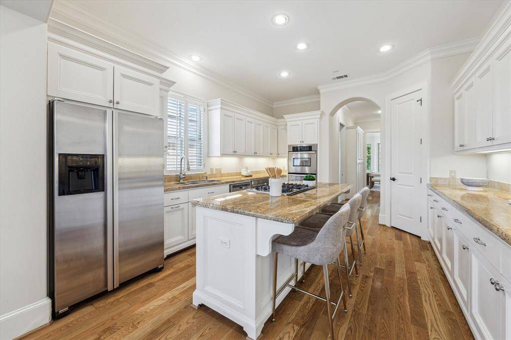 The kitchen is well-equipped with stainless steel appliances, double ovens, two sinks, a breakfast bar, beverage fridge and pantry.