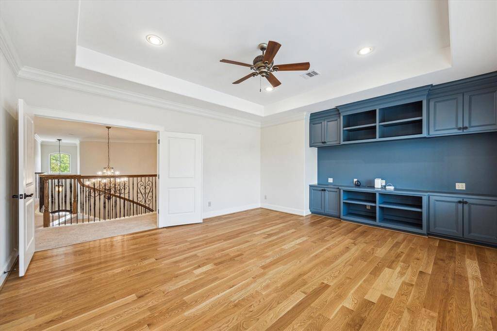 Huge gameroom with double doors, hardwood floors, tray ceiling, built-in shelves and cabinets.