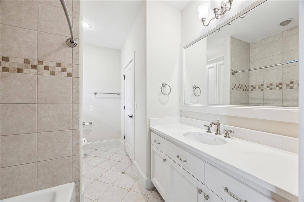 Ensuite bath for secondary bedroom with a shower/ tub combo, ample counter space and storage.