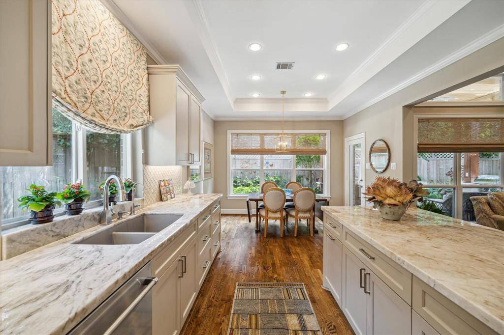 The beautiful quartzite countertops and coordinating backsplash add a modern touch to the kitchen. The breakfast room overlooking the back patio is in view.