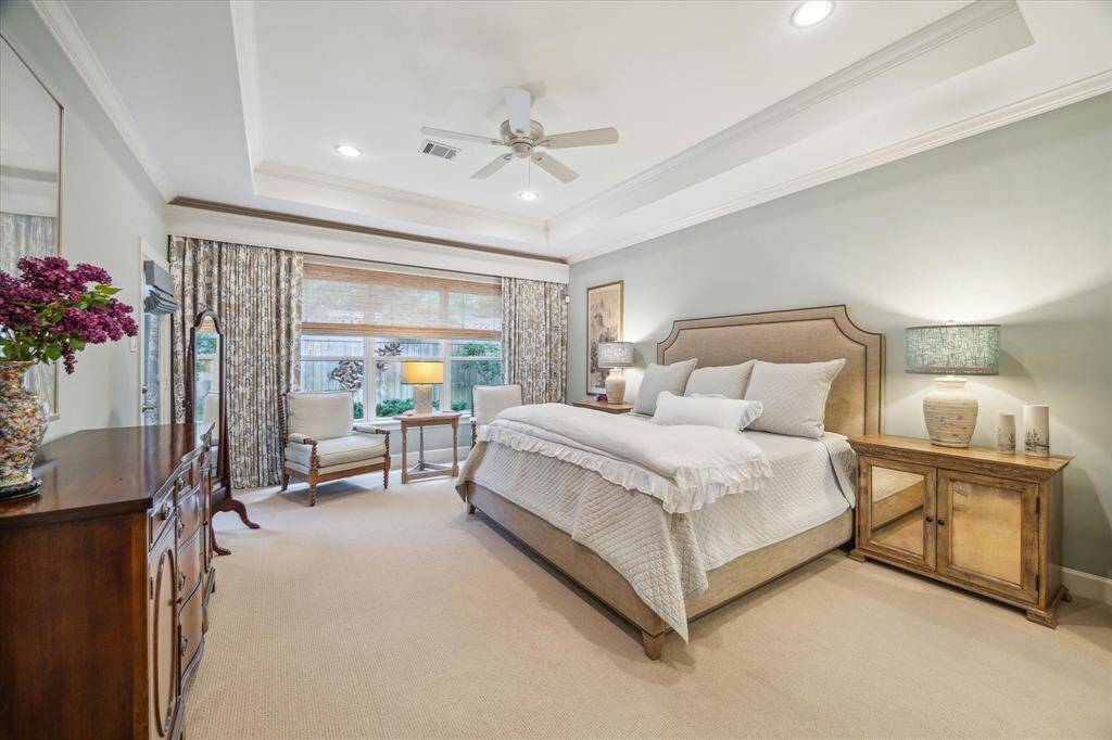 The primary bedroom on the first floor also has coffered ceilings, a door to the back patio and windows overlooking the patio. The automatic drapery opener remains  with the house. (Drapes are excluded)