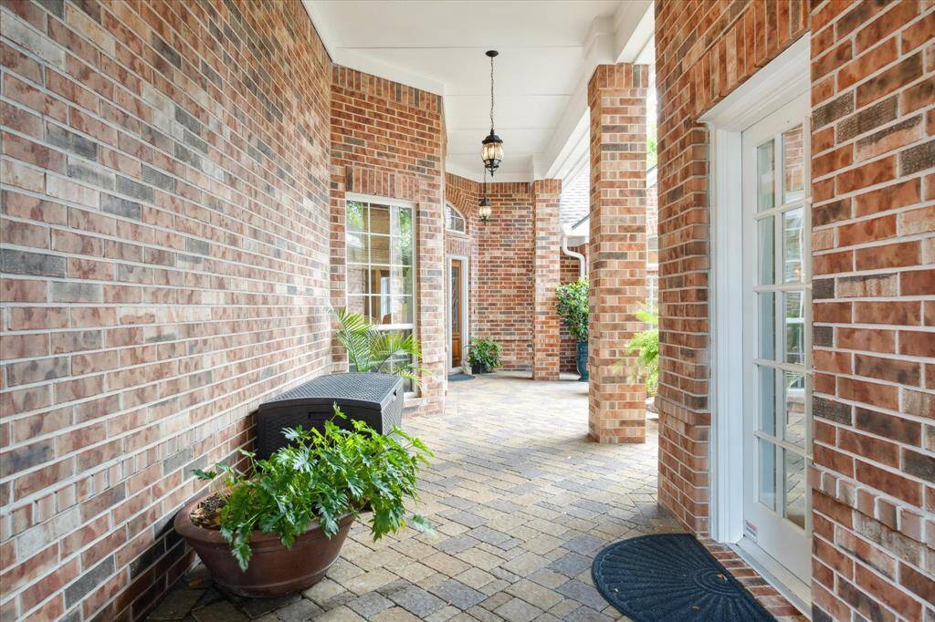 Through the iron gate is an elegant walkway with brick columns and hanging coach lamps to the front door of the home. The doorway to the right is to the casita or private guest suite/office.
