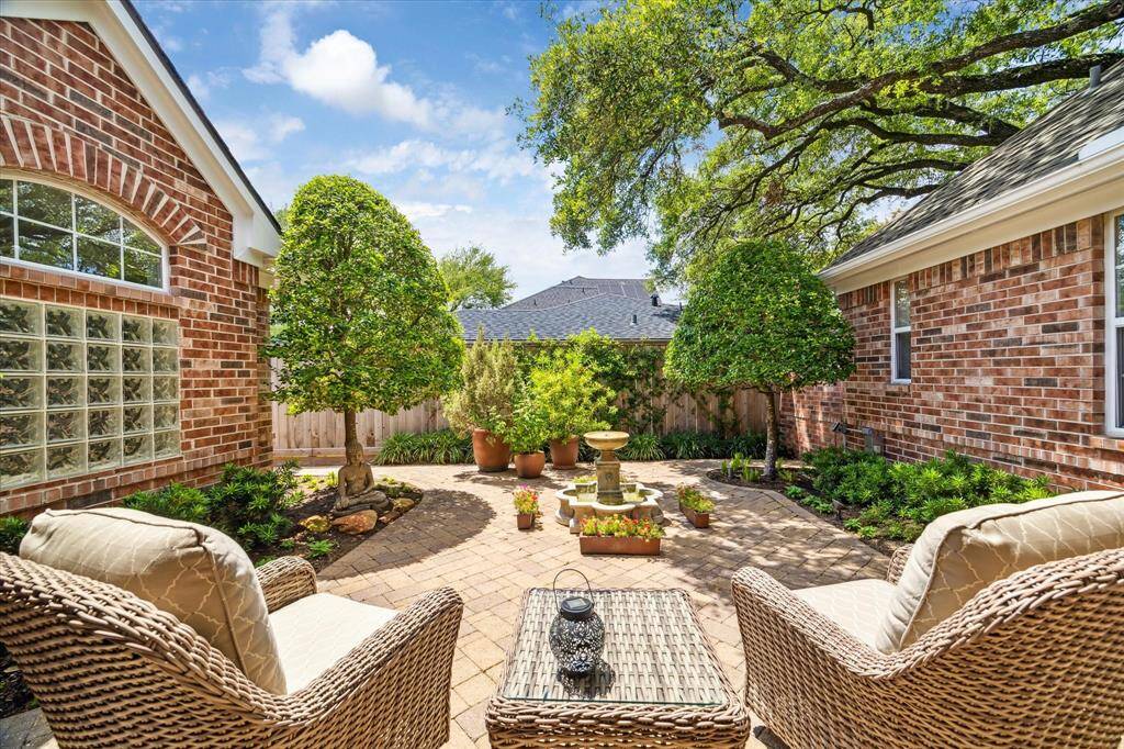 This patio is along the walkway to the house. A bubbling fountain is in the centerof the patio with its manicured trees and lush landscaping.