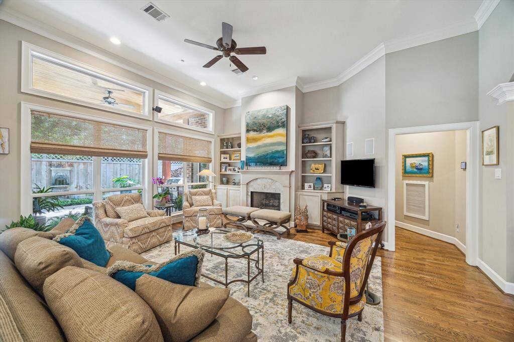 The main living area with its high ceilings, fireplace with a quartzite surround and bookcases has views of the back patio and covered porch. The doorway to the right is the entrance to the primary bedroom.