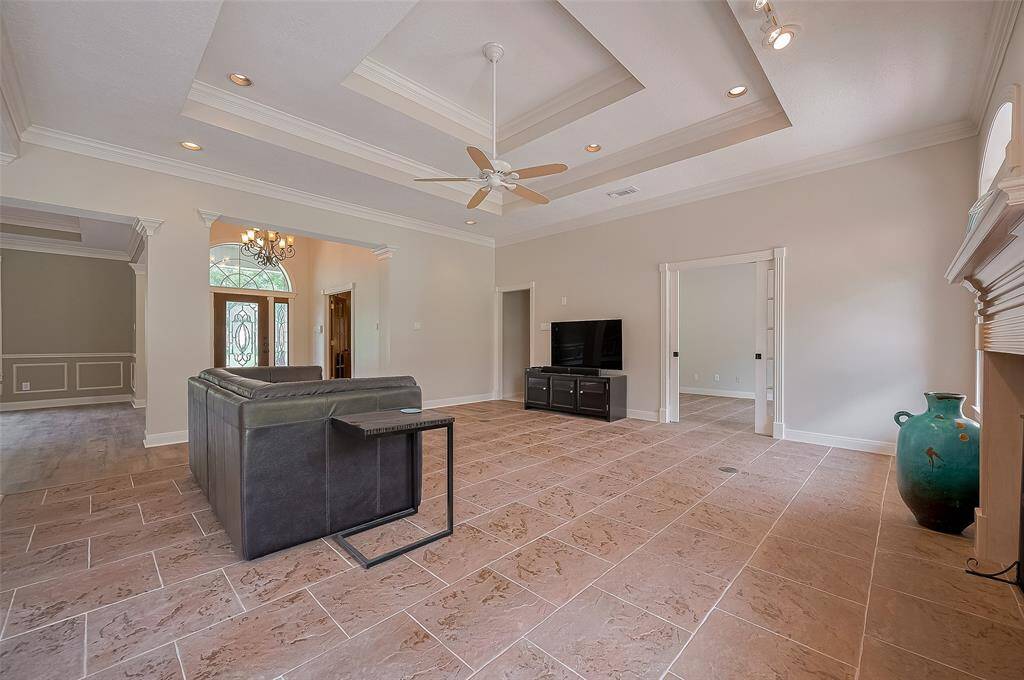 This photo highlights the tile flooring, two-tiered tray ceiling, recessed lighting.  The wide, open doorway at the back iis the flex room.   The smaller doorway leads to the bedroom hall.