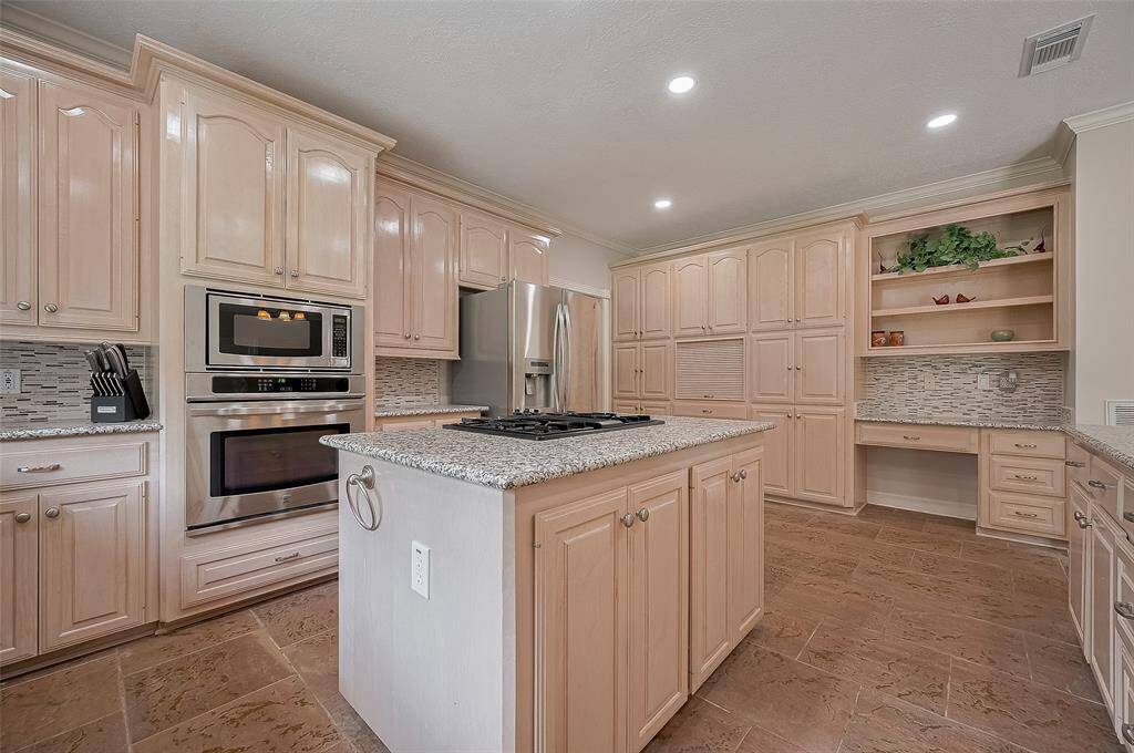 Island Kitchen with Granite Counters, Stainless Steel Appliances, Abundant Cabinetry, and a full Wall of Built-ins for incredible storage