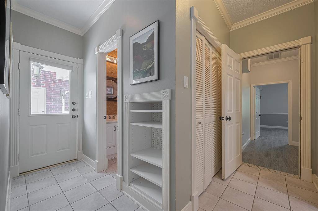 This photo shows the part of the home on the back side of the kitchen.  Flex room (that was converted from the original garage)  is thru the open dooway to the right.  Half bath is just past the handy built-in nook. Perfect for dropping off shoes, backpacks when you come in the house. . The door to the added garage / porte cochere.  Photo was taken from door to laundry room.
