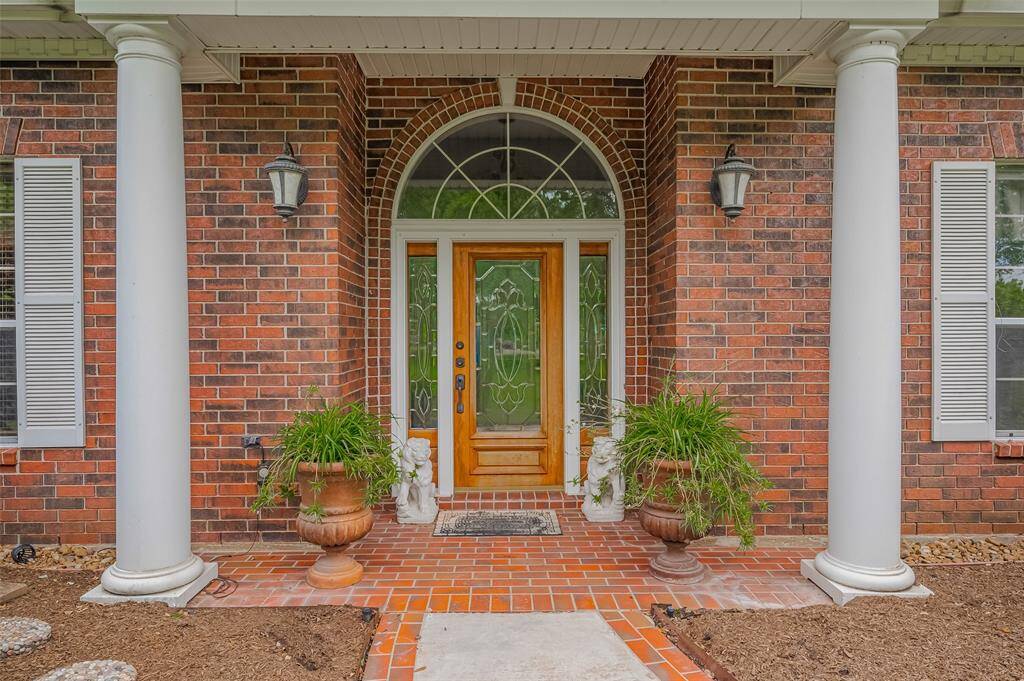 Welcoming front entry with classic pillars, bricked front porch. The glass front door, sidelights and arched transom window allow an abundance of natual light inside.