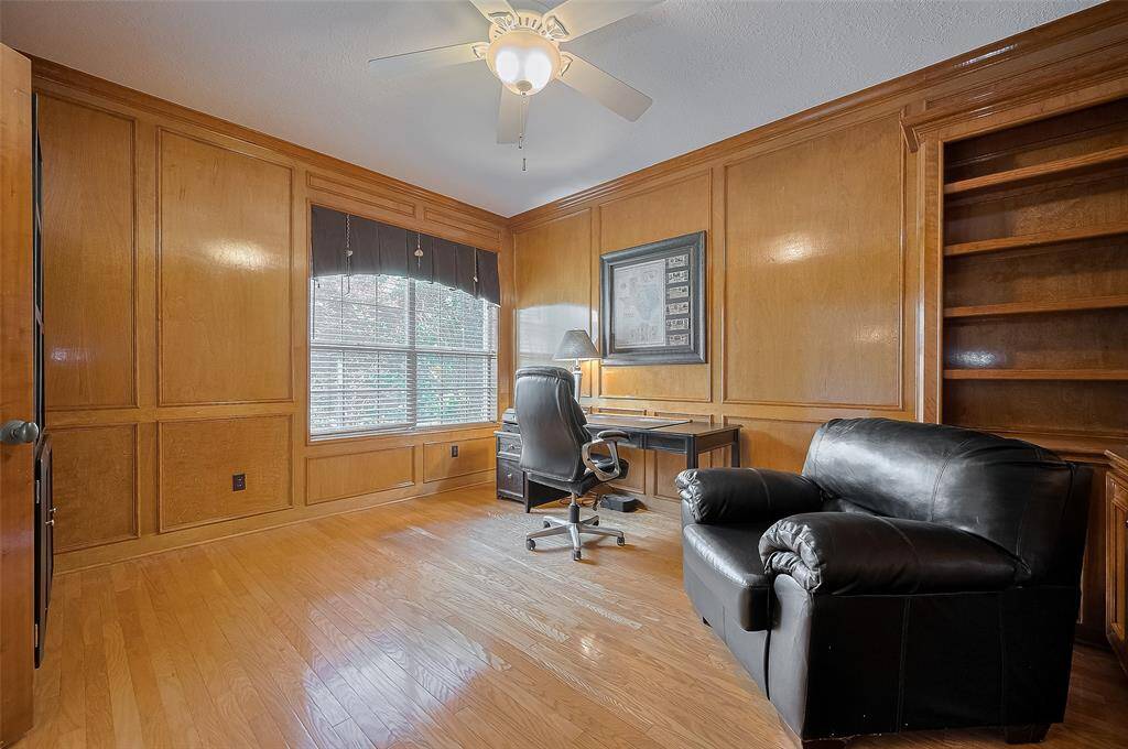 This expansive home office offers French doors for privacy, gleaming wood flooring and tradition wood paneling . . .