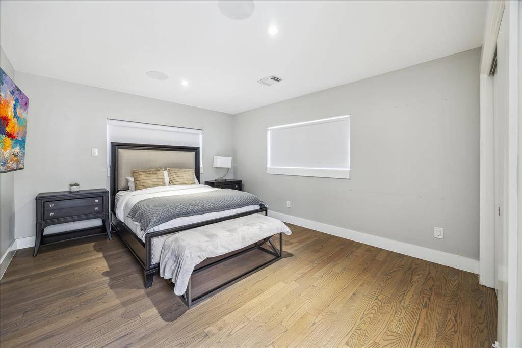 This bedroom features a modern design with hardwood floors and neutral walls.  The room is well-lit with natural light from a window.