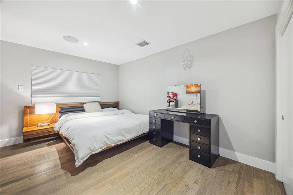 This is a bright, modern bedroom has light walls and hardwood flooring, creating a cozy yet contemporary atmosphere.