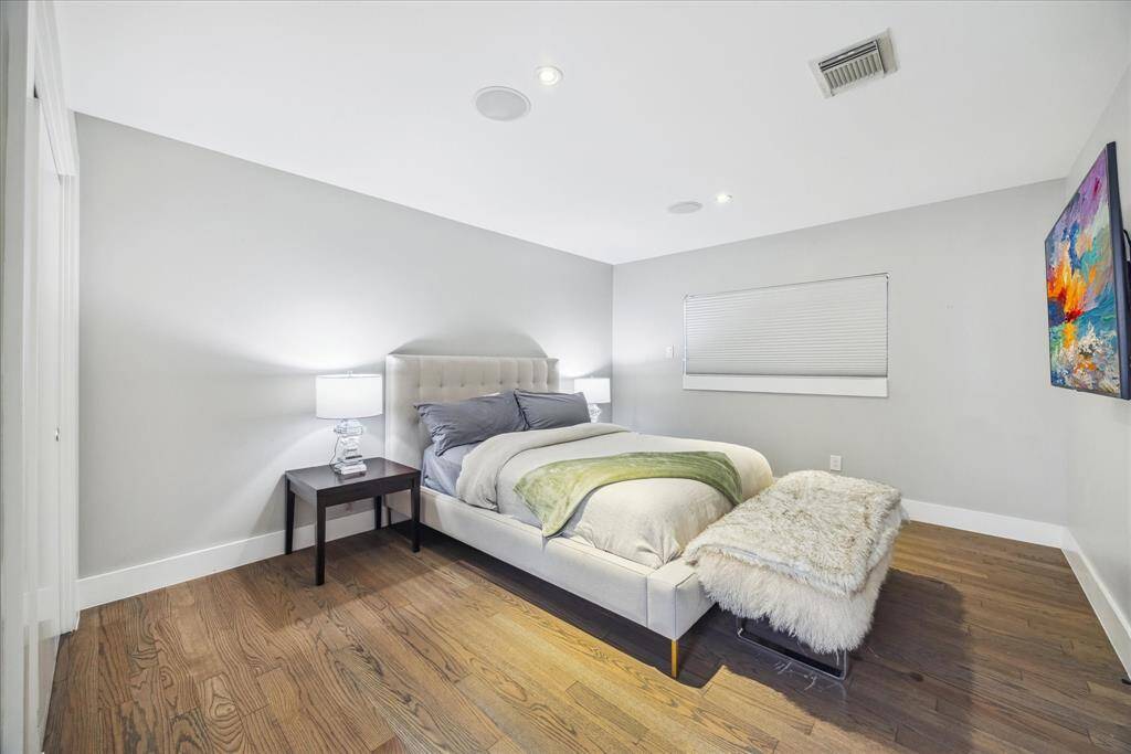 This bedroom features a modern design with neutral gray walls and hardwood flooring.