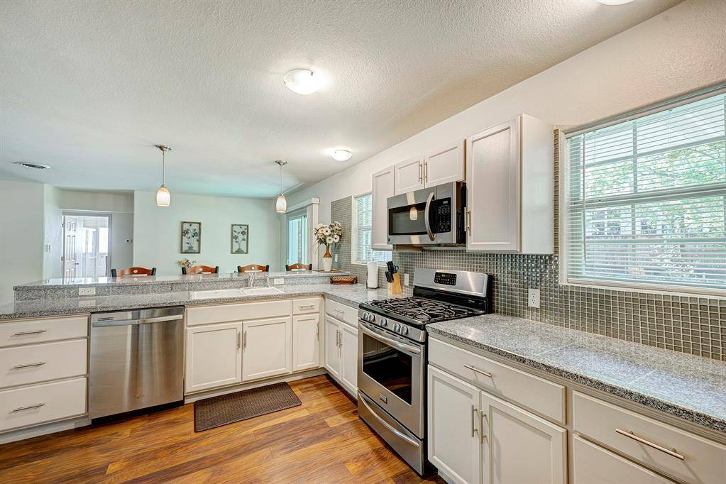 Bright and spacious kitchen with modern appliances, granite countertops, and ample cabinet space. Features a breakfast bar and large windows for natural light. Ideal for cooking and entertaining.