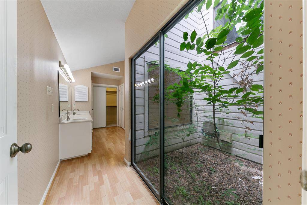 Floor-to-ceiling glass windows open to a private garden, creating a serene view and seamless indoor-outdoor connection.