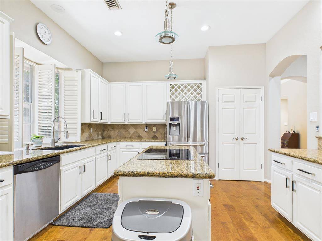 kitchen features an island cook top, tons of counter space and cabinets, Fridge conveys with the home, large pantry, wine rack.