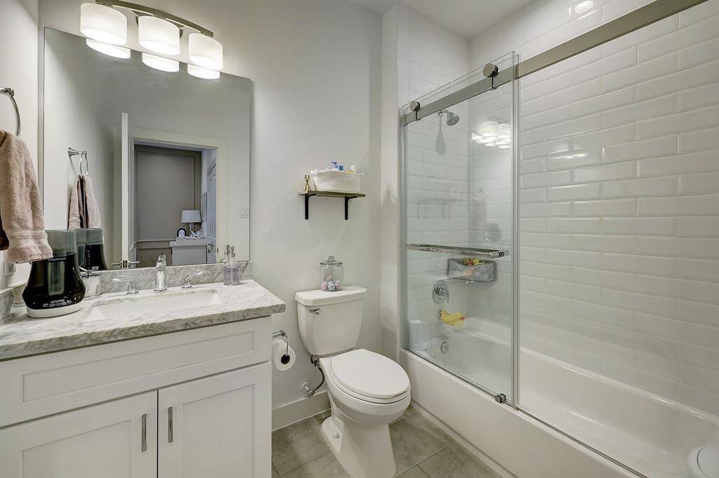 En suite bathroom for the secondary, third floor bedroom includes a combo tub and shower with glass sliding door that makes the space feel larger.