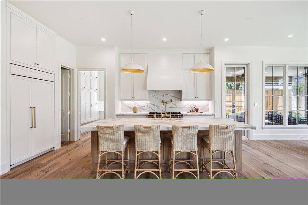 The beautiful kitchen features large island with barstool seating, paneled fridge, and double ovens.