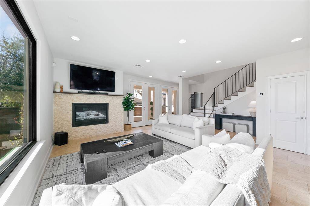 The stone-encased gas log fireplace defines the living area, creating a cozy ambiance and inviting family and friends to relax in style.  The huge picture window and double set of French doors leading to the covered porch out back combine to unite the gorgeous indoor and outdoor living spaces.
