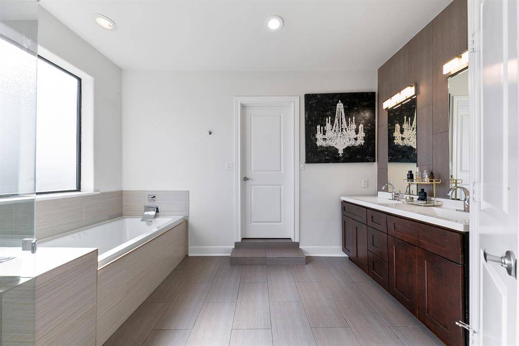 The spacious primary bathroom is a spa-like sanctuary, featuring sleek porcelain tile flooring that complements the modern fixtures and finishes.  A porcelain-encased soaking tub allows for luxurious relaxation, while the separate glass shower cabin offers a refreshing escape to wash away the cares of the day.  The massive walk-in closet with designated dressing areas for both of the primary homeowners will not disappoint.