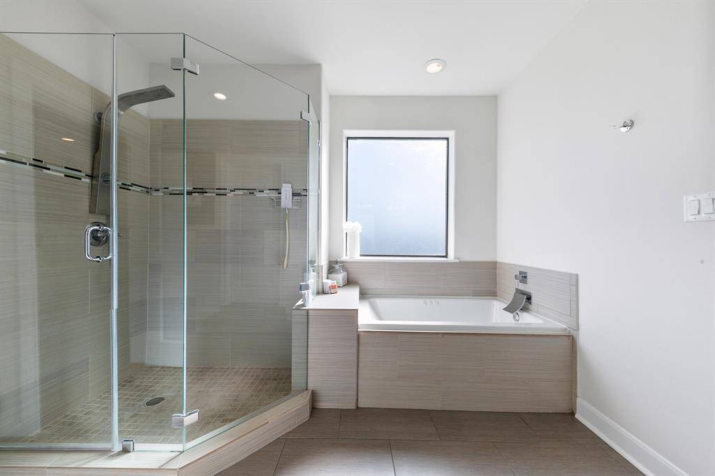 The glass shower cabin is a standout feature, complete with a rain showerhead and seamless glass surround.